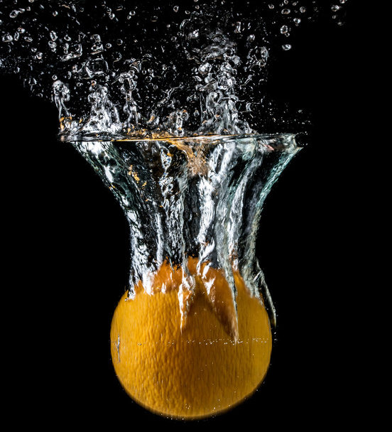 Orange falling into the water close-up, macro, splash, bubbles, black background - Photo, Image