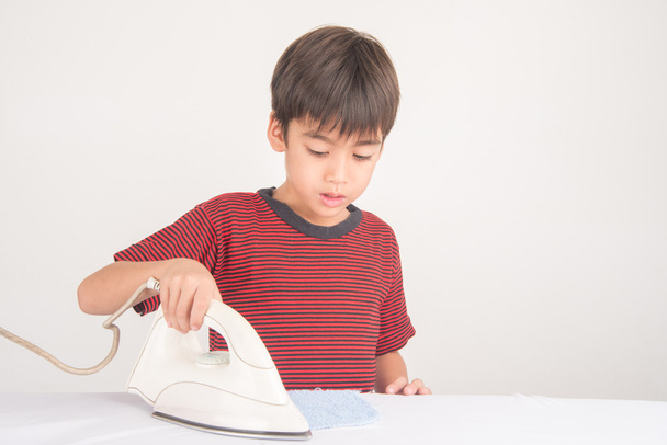 Little boy ironing his cloth helping of house work - 写真・画像