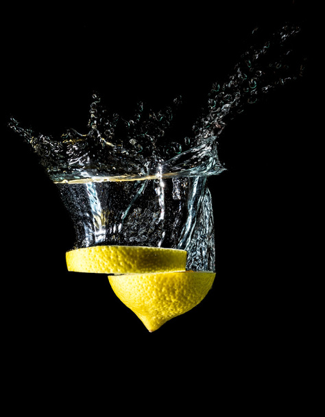 Lemon slices falling into the water close-up, macro, splash, bubbles, isolated on black  - Photo, Image