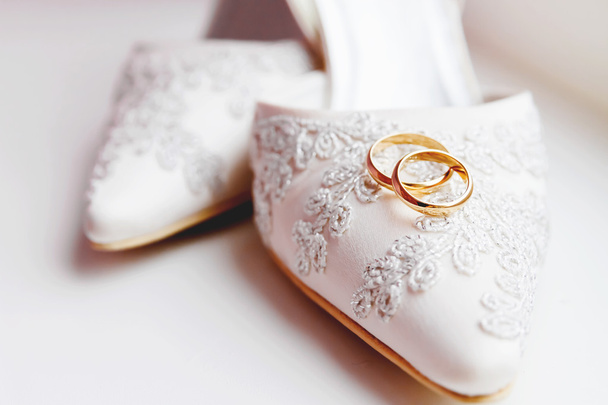Золоті обручки на мереживному шовковому тканинному взутті. Весільні ювелірні деталі. Символ кохання і шлюбу
. - Фото, зображення
