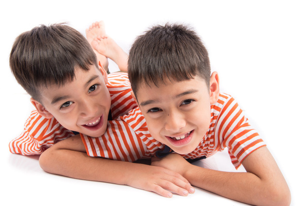 Little siblings boy brother smiling laying down together with happy face on white background - Photo, Image