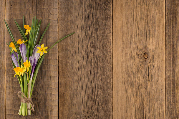 Daffodils and crocuses on the old wooden table. - Foto, afbeelding