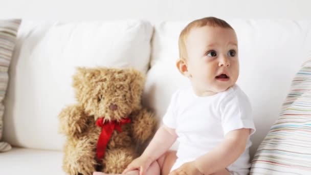 baby with teddy bear sitting on sofa at home 6 - Video, Çekim