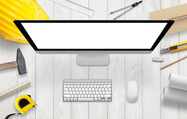Ordenador con pantalla aislada, blanca y en blanco en el escritorio del sitio de construcción
. - Foto, imagen