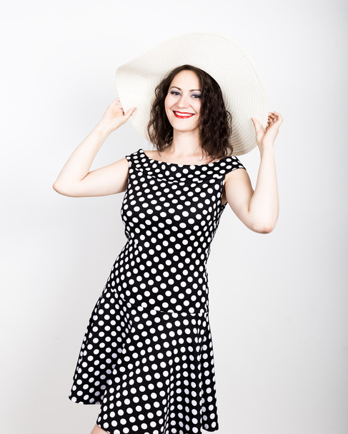 beautiful young brunette woman holding a broad-brimmed hat, she expression of different emotions. wears a dress with polka dots - Valokuva, kuva