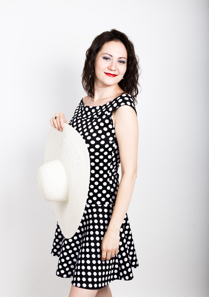 beautiful young brunette woman holding a broad-brimmed hat, she expression of different emotions. wears a dress with polka dots - Fotoğraf, Görsel