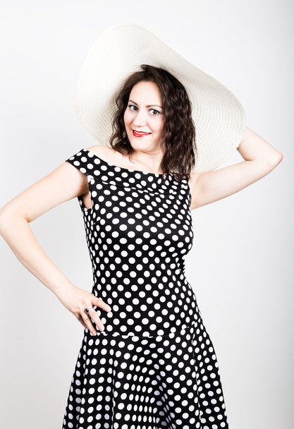 beautiful young brunette woman holding a broad-brimmed hat, she expression of different emotions. wears a dress with polka dots - Fotografie, Obrázek