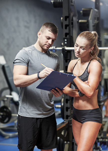 young woman with personal trainer in gym - 写真・画像