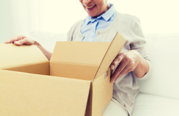 close up of senior woman with parcel box at home - Foto, afbeelding