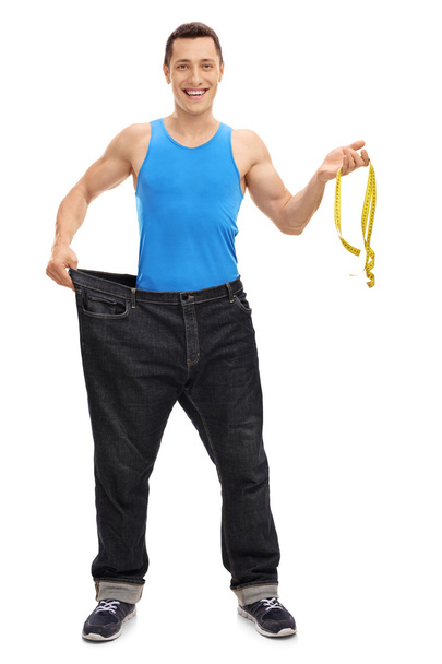Slim man holding a measuring tape  - Foto, imagen