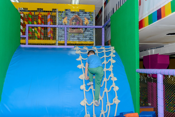 Маленький мальчик скользит по изогнутой пластиковой горке
 - Фото, изображение