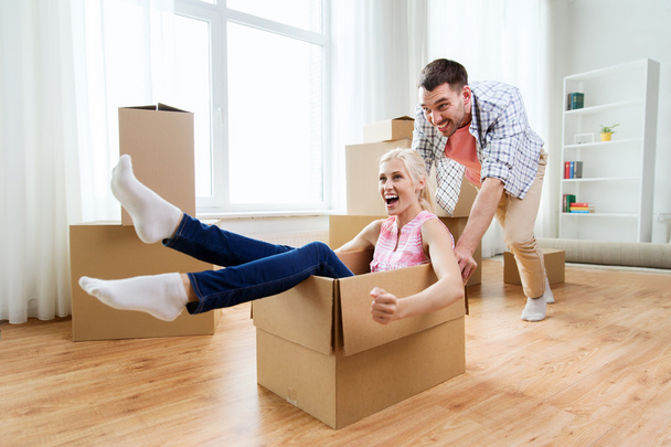 couple with cardboard boxes having fun at new home - Foto, afbeelding