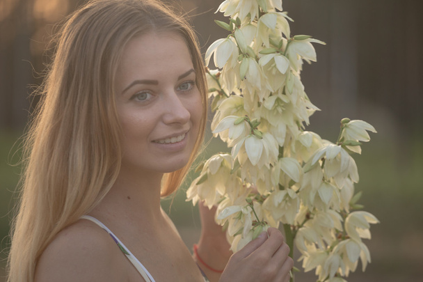 ritratto primo piano.. Giovane bella bella donna in posa in abito lungo contro nel campo con fiori bianchi
 - Foto, immagini