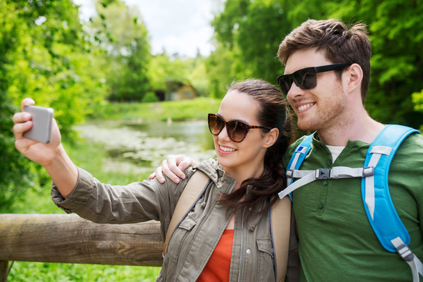 couple with backpacks taking selfie by smartphone - Foto, Imagen