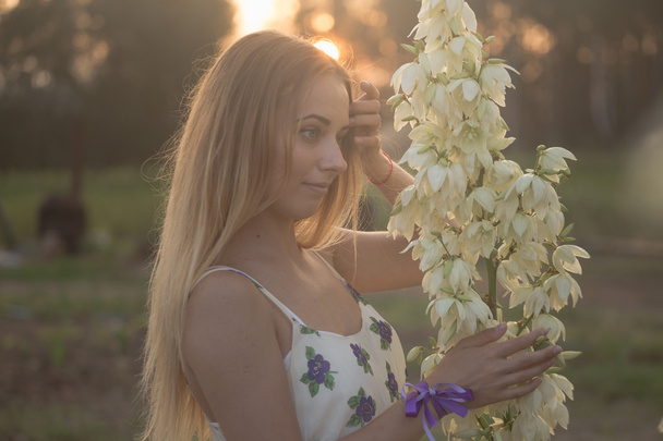 close-up portrait.. Young beautiful pretty woman posing in long dress against in the field with white flowers - Photo, Image