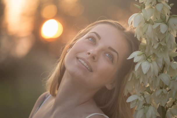Close-up portret... Prachtige mooie jongedame poseren in lange jurk tegen in het veld met witte bloemen - Foto, afbeelding