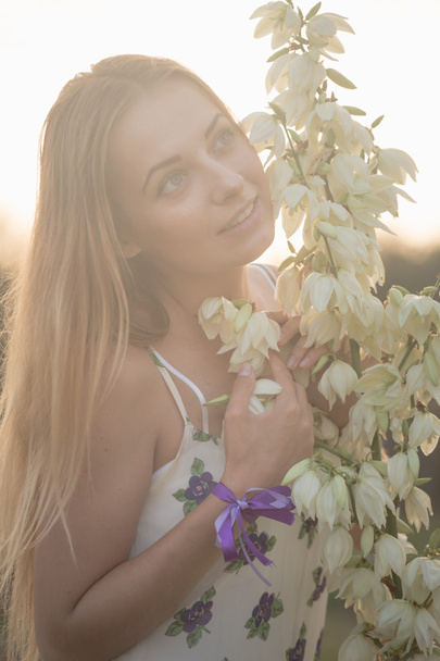 retrato de cerca.. Joven hermosa mujer bonita posando en vestido largo en contra en el campo con flores blancas
 - Foto, Imagen