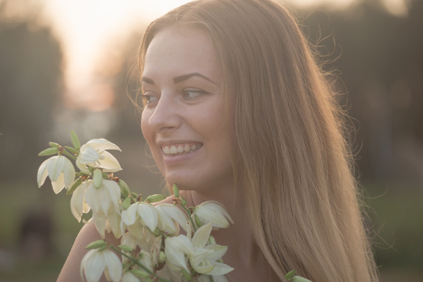retrato de cerca.. Joven hermosa mujer bonita posando en vestido largo en contra en el campo con flores blancas
 - Foto, Imagen