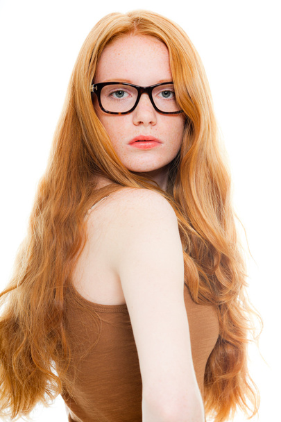 Jolie fille aux longs cheveux roux portant une chemise marron et des lunettes vintage. Studio de mode tourné isolé sur fond blanc
. - Photo, image
