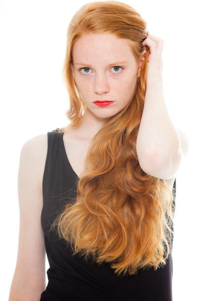 Pretty girl with long red hair and lipstick wearing black shirt. Fashion studio shot isolated on white background. - Фото, изображение