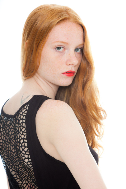 Pretty girl with long red hair and lipstick wearing black shirt. Fashion studio shot isolated on white background. - 写真・画像