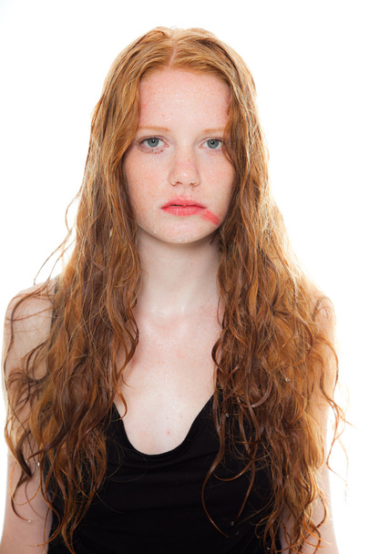 Pretty girl with long red hair wearing black shirt. Wet hair and face looking sad. Fashion studio shot isolated on white background. - 写真・画像
