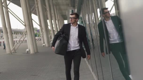 Young businessman pulling suitcase in modern airport terminal. Travelling guy concept - Video