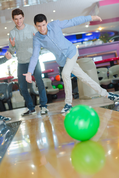 Two young men enjoying a game of ten pin bowling - Фото, изображение