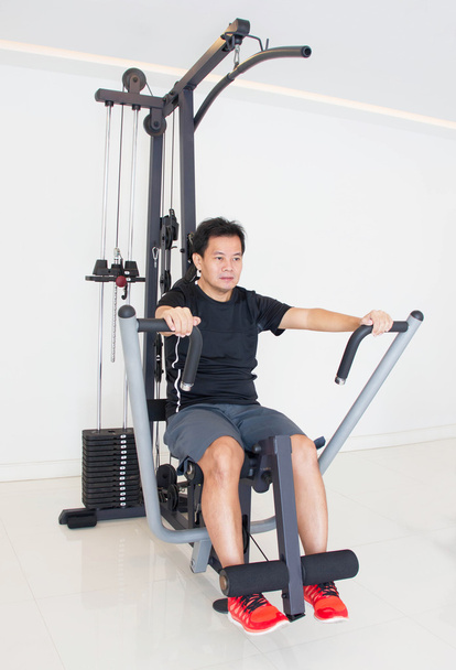 Asiatique homme faisant de l'exercice sur la machine de remise en forme dans le gymnase
. - Photo, image