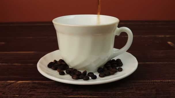 Verter una taza de café con granos de café en el plato sobre la mesa de madera marrón
 - Metraje, vídeo