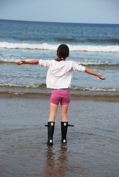 Küçük kızın arkadan görünüm denizin önünde mutlu duruyor - Fotoğraf, Görsel