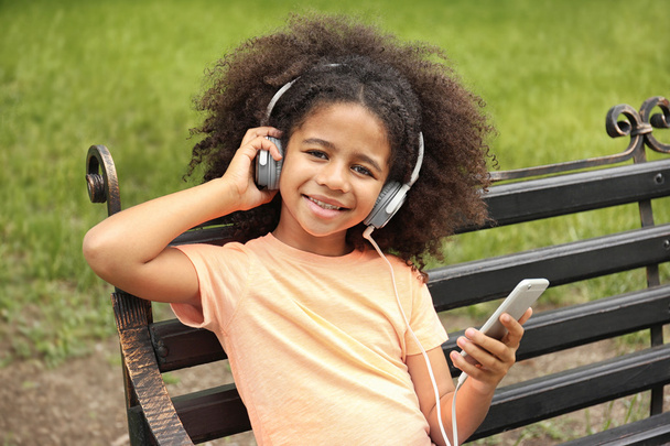Afro-American little girl listening to music  - Фото, изображение