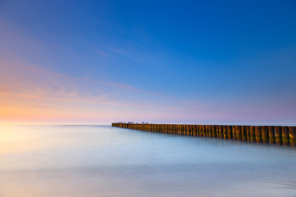 sunset on the beach with a wooden breakwater, long exposure - Photo, Image