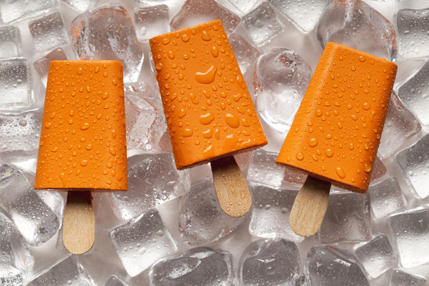 Orange ice lollies on ice cubes  - Foto, imagen