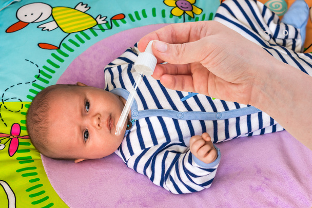 Новорожденный получает капли носа с солевым раствором
 - Фото, изображение