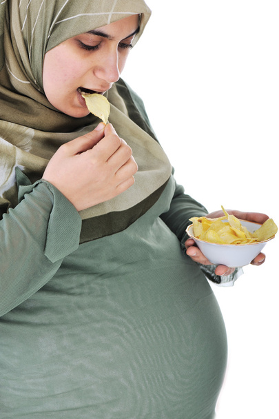 zwangere vrij Moslimvrouw eet chips - Foto, afbeelding