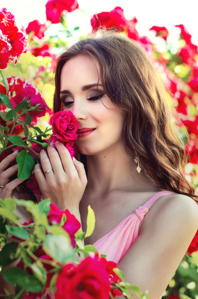 Portrait of a beautiful girl on a background of roses - 写真・画像