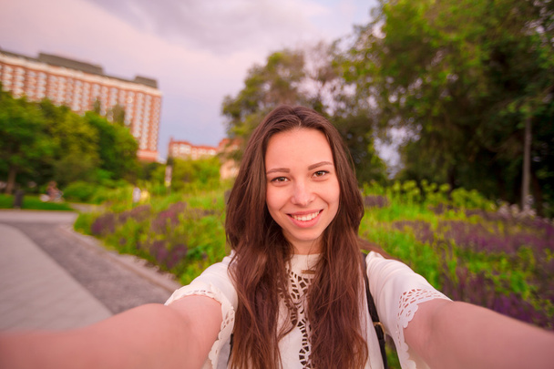 Mladá běloška dělá selfie na atrakcí pozadí venku. Šťastná dívka vychutnat její víkend v evropském městě - Fotografie, Obrázek