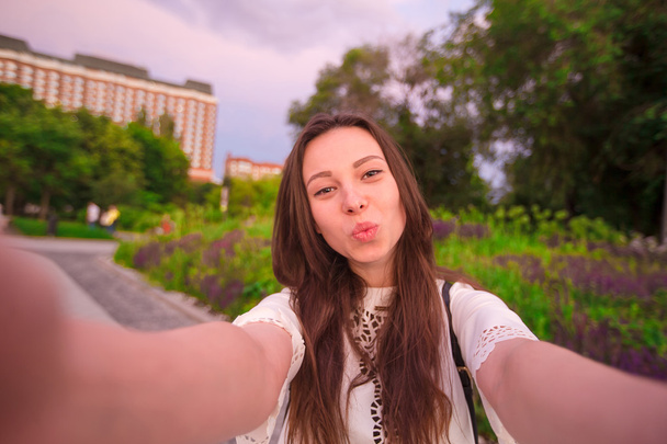 Jeune fille faisant du selfie vidéo et s'amusant dans le parc. Lifestyle selfie portrait de jeune femme positive s'amuser et prendre selfie. Concept fun avec les nouvelles tendances et technologies
. - Photo, image