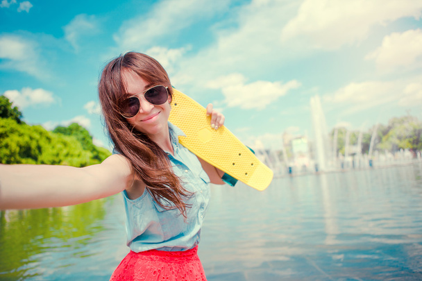 Menina se divertindo com skate no parque. Estilo de vida retrato de jovem mulher positiva se divertindo e desfrutar de tempo quente
. - Foto, Imagem