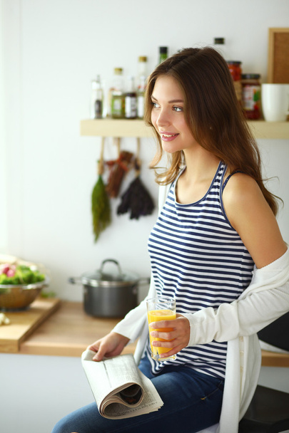 Young woman sitting near desk in the kitchen - Foto, Imagen