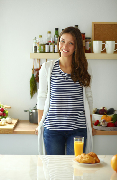 Young woman with glass of juice and cakes standing in kitchen . - Photo, Image