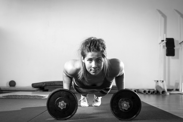 Girl doing push ups with dumbbell - Фото, зображення