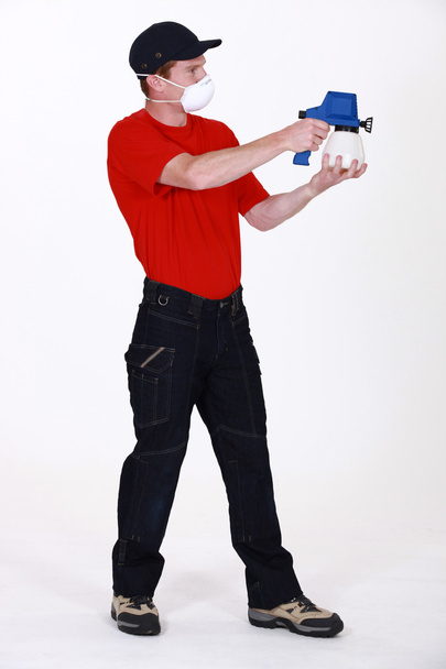 Man wearing face mask whilst using paint sprayer - Фото, зображення