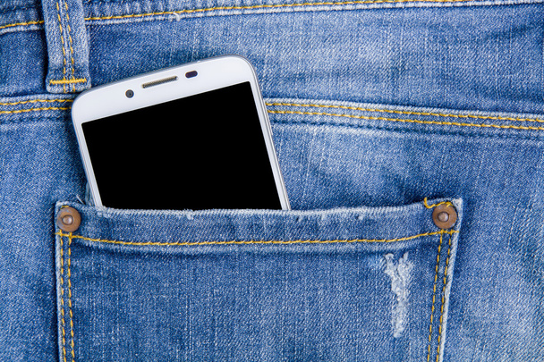 Inteligentny telefon w tylnej kieszeni spodni jeans. Tło dżinsy. - Zdjęcie, obraz
