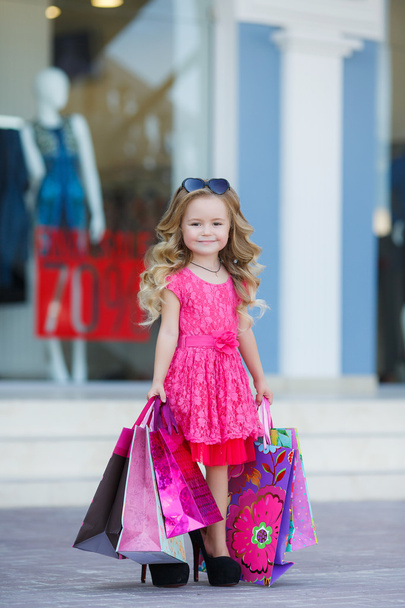 Cute little girl with colorful bags for shopping in supermarket - Foto, Imagen