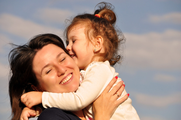 glückliche Mutter umarmt ihre Tochter gegen den Himmel - Foto, Bild