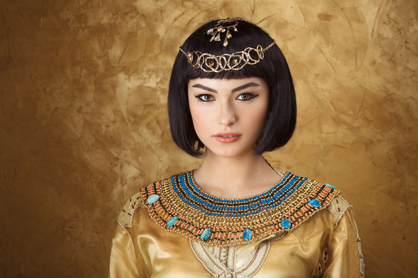Beautiful woman like Egyptian Queen Cleopatra on golden background - 写真・画像
