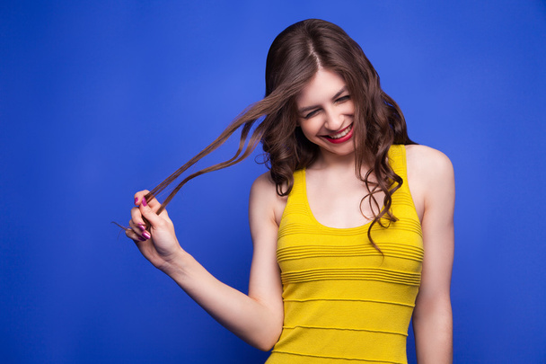 Cheerful model in yellow dress pulling her hair - Photo, image