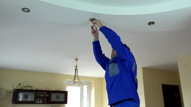 Hombre electricista calificado instalar o reemplazar la lámpara de luz halógena spot en el techo
 - Imágenes, Vídeo